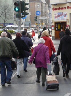 Jüngere und ältere Menschen überqueren eine Fußgängerampel bei „Grün“