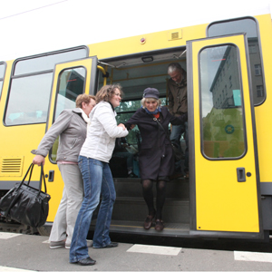 Eine junge Frau hilft einer älteren Dame aus der Straßenbahn